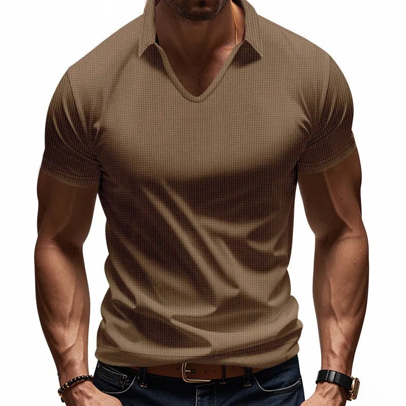 Man wearing a loose-fitting apricot V-neck short sleeve t-shirt against a plain background.