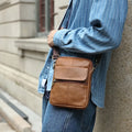 Men's brown genuine leather crossbody shoulder bag with sewing line detailing.