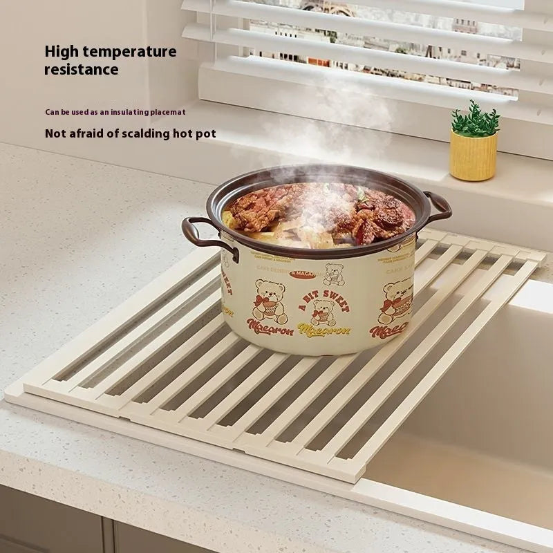 Foldable milky white stainless steel kitchen draining rack next to a sink.
