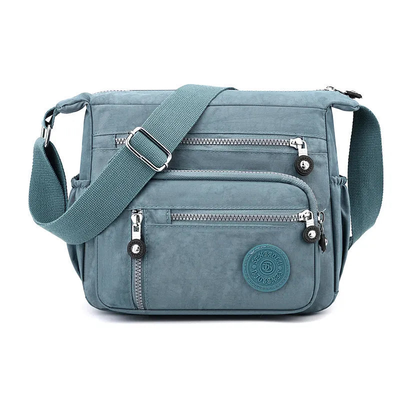 Grey nylon shoulder messenger bag with a single strap and square vertical shape on a neutral background.