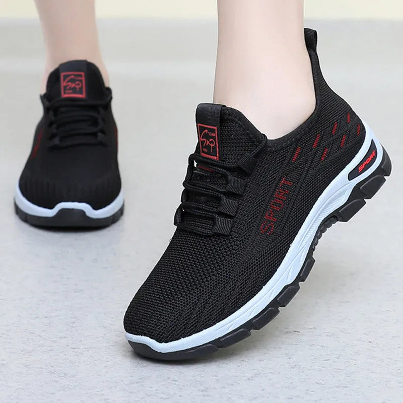 Man and woman wearing low-top casual sneakers in black and red with round toes and PVC soles.