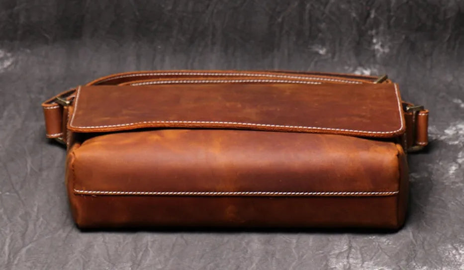 Vintage brown leather mens messenger bag with a shoulder strap, shown open to reveal internal organiser pockets.
