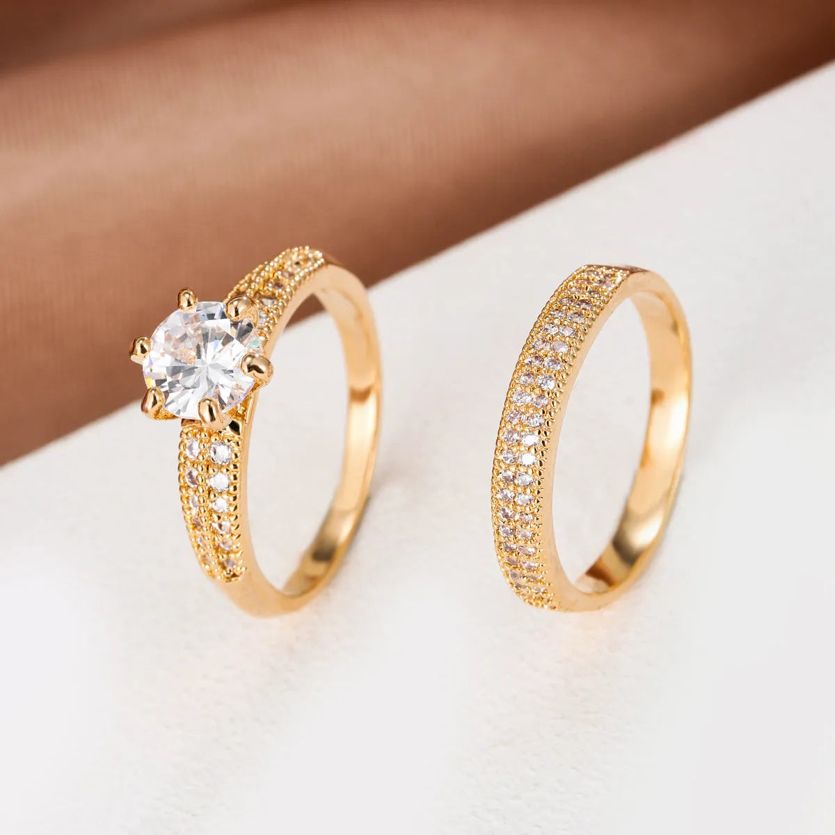 Two copper zircon hollow geometric rings with electroplated colour finish on white background