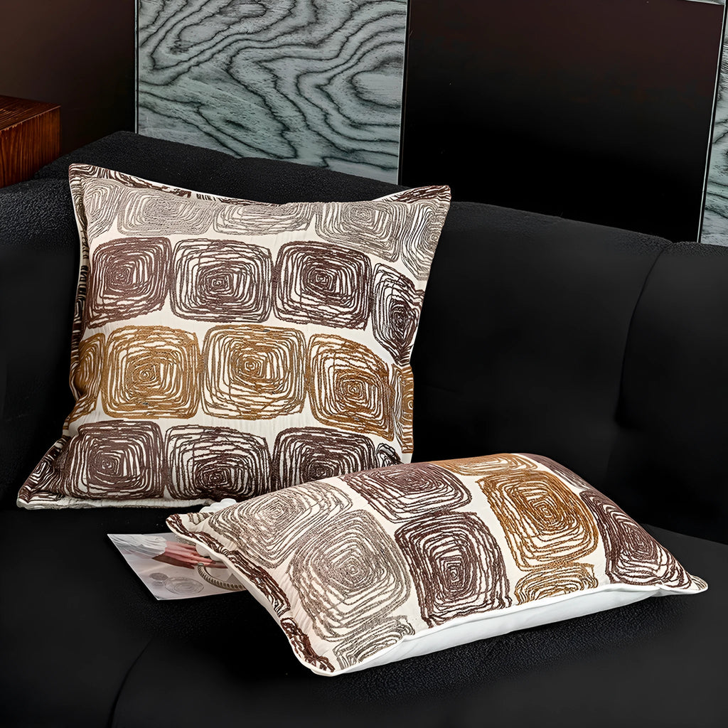 Cream and coffee-coloured abstract coil pattern on a square decorative pillow cover.