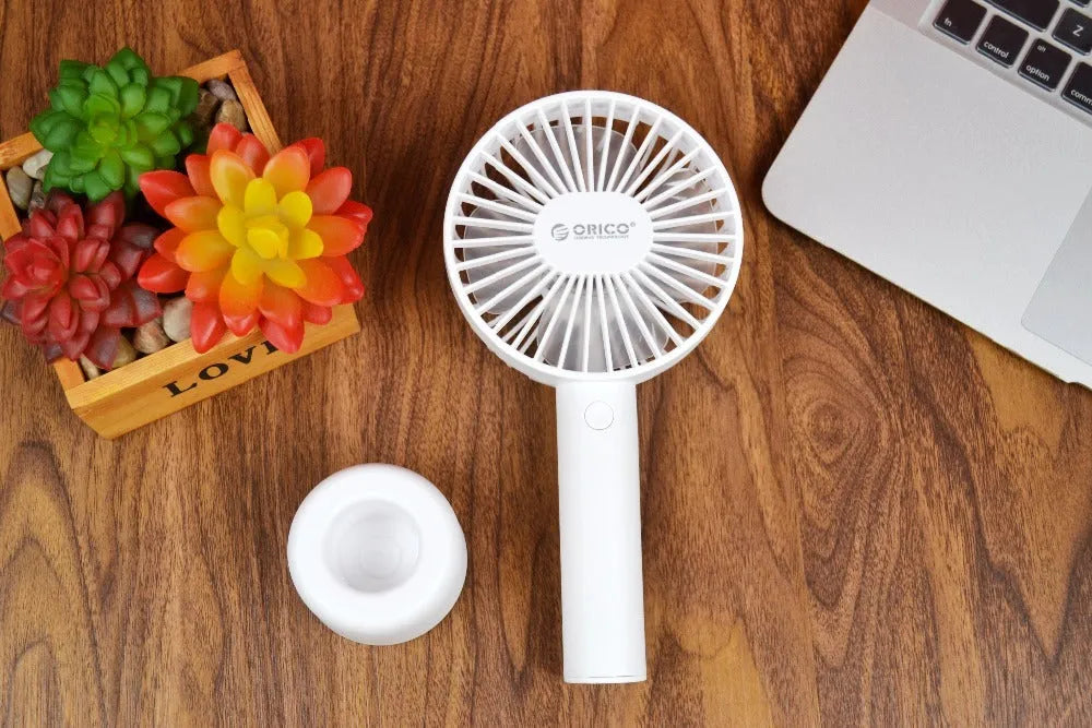 White ORICO FH1 handheld USB rechargeable small fan with three-speed buttons on a desktop.