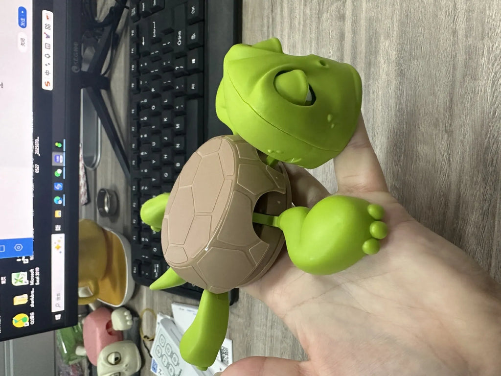 Turtle-shaped ABS plastic coaster in light green colour on a wooden table.