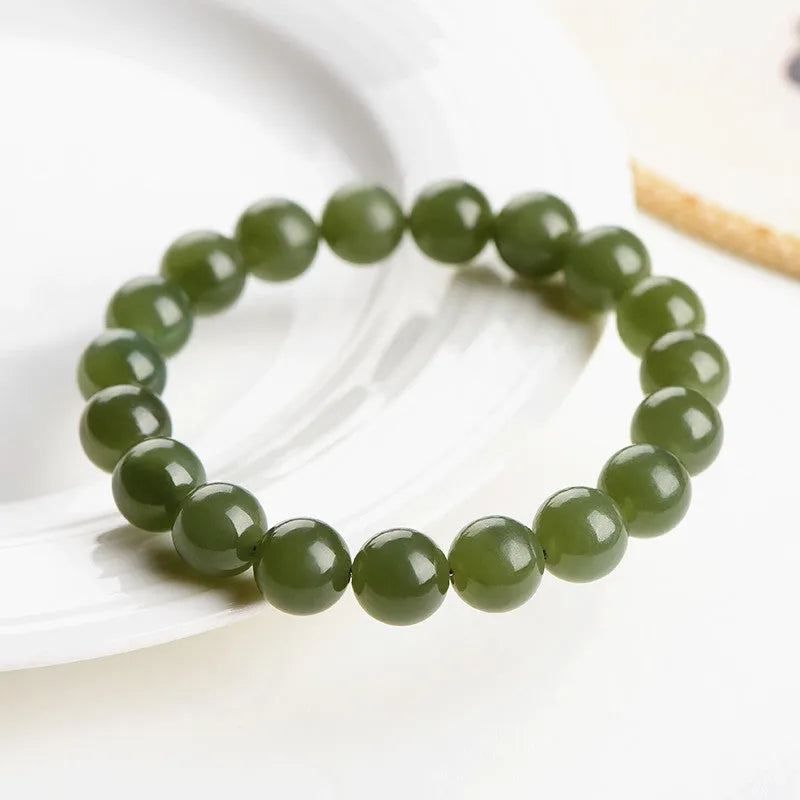 Polished Hetian jade ball bracelet in clear water colour on a wrist, showing spherical beads.