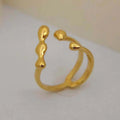 Brass opening ring with spherical element in gold colour on a hand.