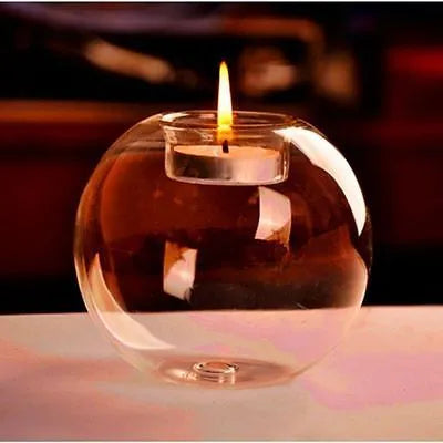 Handmade round hollow glass candle holder in three sizes on a wooden table.