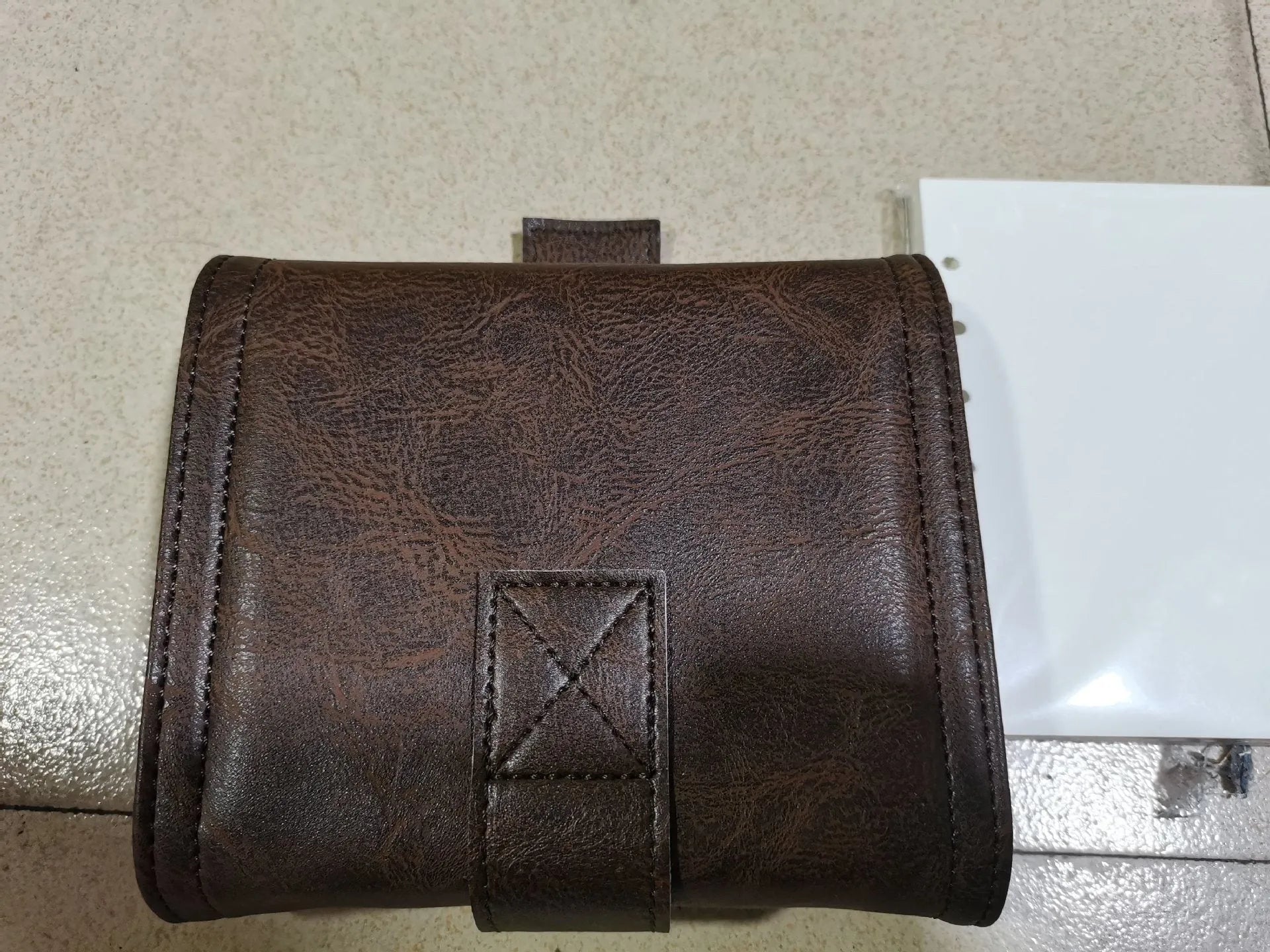 Brown A7 notebook with leather-style buckle closure showing loose-leaf binding