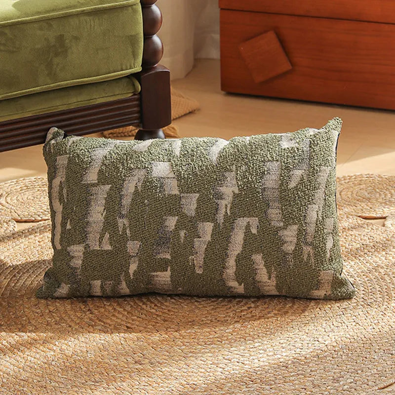 Square jacquard cushion cover with woven floral pattern on a grey sofa, showing zip closure and textured fabric.
