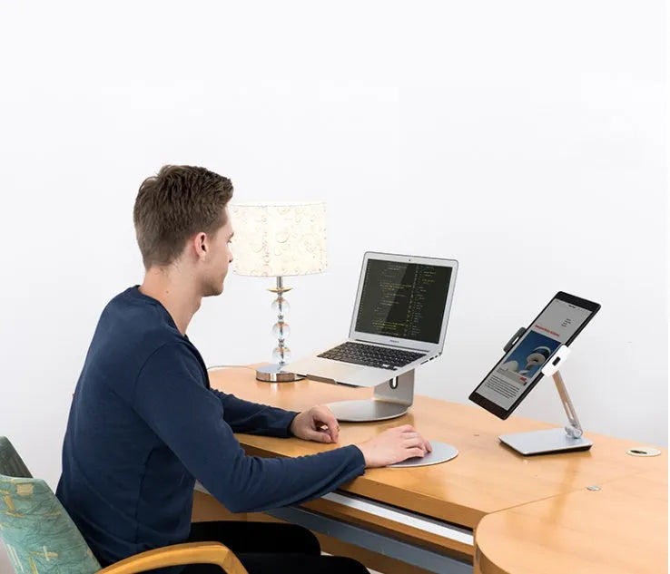 Folding aluminium and black plastic phone tablet stand on a desk, showing 360 degree rotation base.