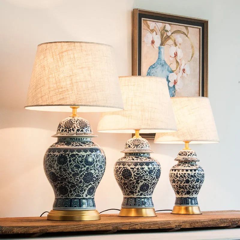 Blue and white porcelain Chinese table lamp with copper base and cloth shade on bedside table