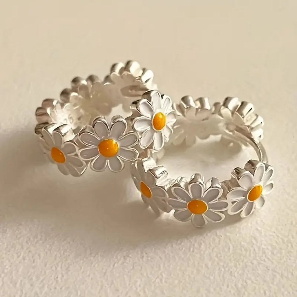 A pair of white daisy flower ring earrings with platinum inlaid gemstones on a copper base.