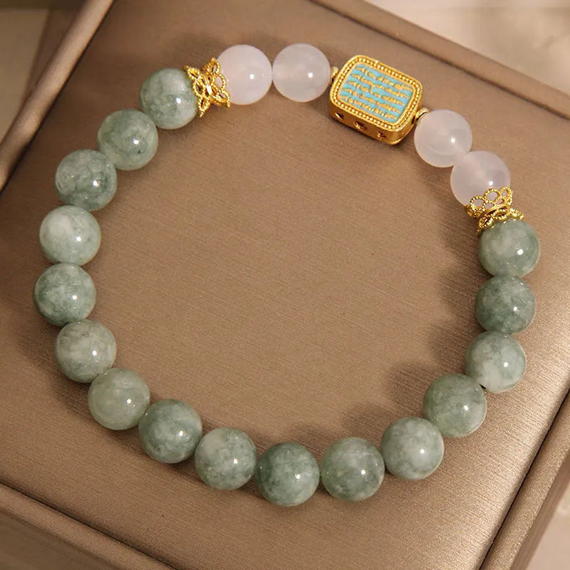 Natural crystal bracelet for women oil green emerald colour with sutra carvings on a white background