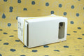 Pink and white cardboard VR glasses viewer for smartphones with 3D lenses.