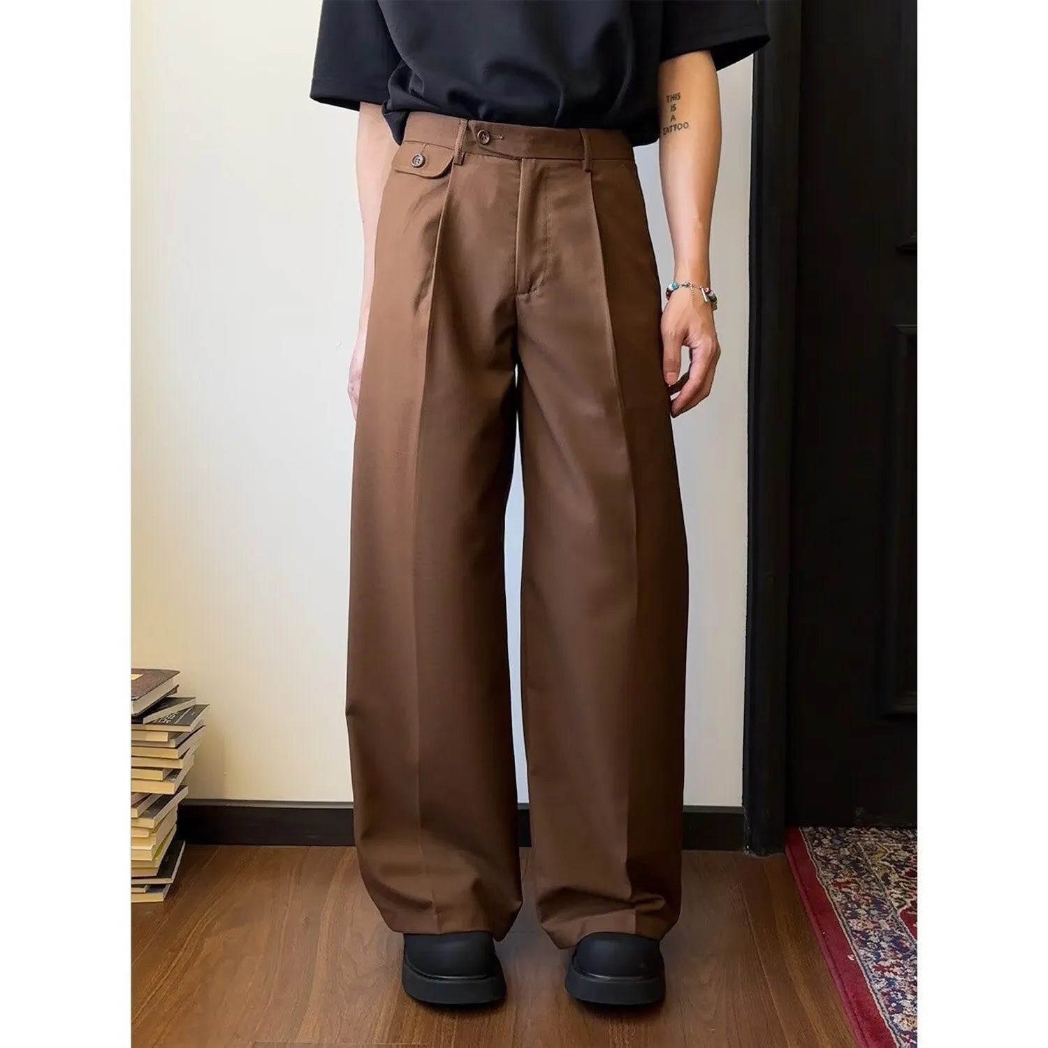 Men's brown straight-leg casual suit trousers with a loose, wide-leg fit on a hanger.