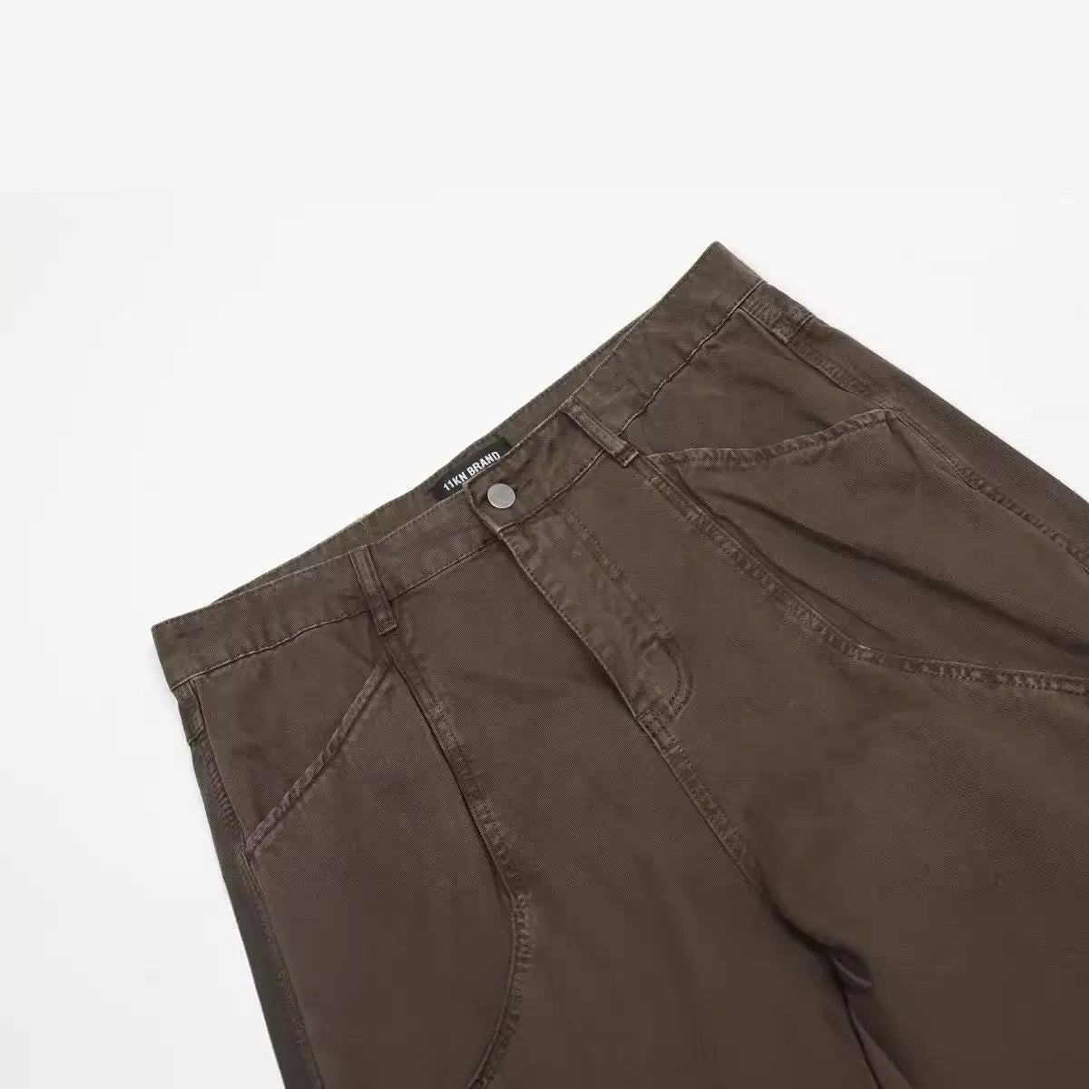 Men's brown loose straight-leg cotton trousers with a high waist and zipper fly.
