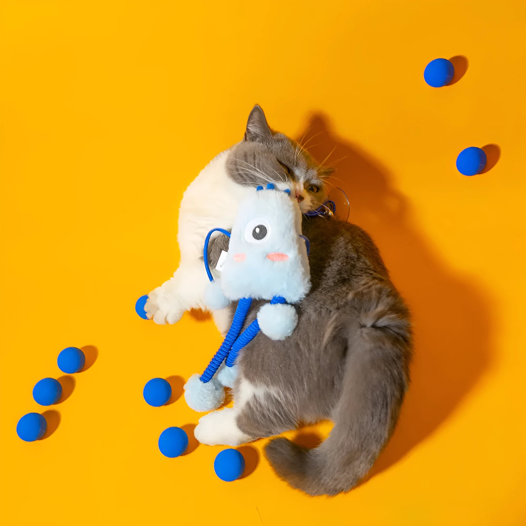 Blue plush cat toy with mint bell and elastic rope on floor