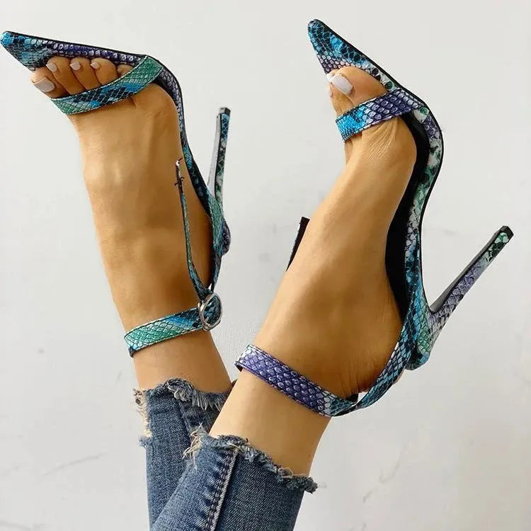 Blue women's high heels with a buckle strap and decorative hollow out design on a pointed toe.