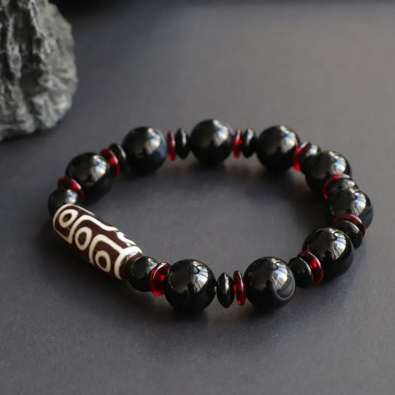 Hand-woven black agate Dzi bead bracelet on a wrist, showing geometric bead and woven band.