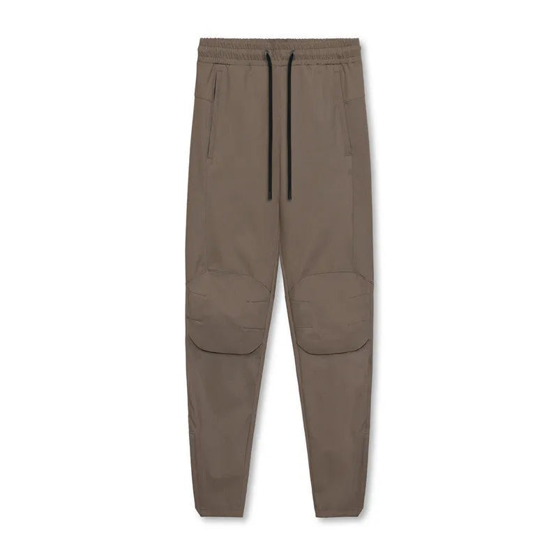 Man wearing dark grey quick-dry fitness trousers with ankle ties, suitable for running and gym workouts.