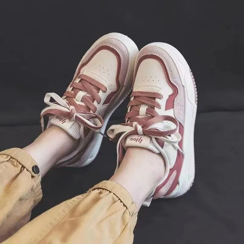 Women's low-top pink and white sneakers with a rubber sole and imitation leather lining.