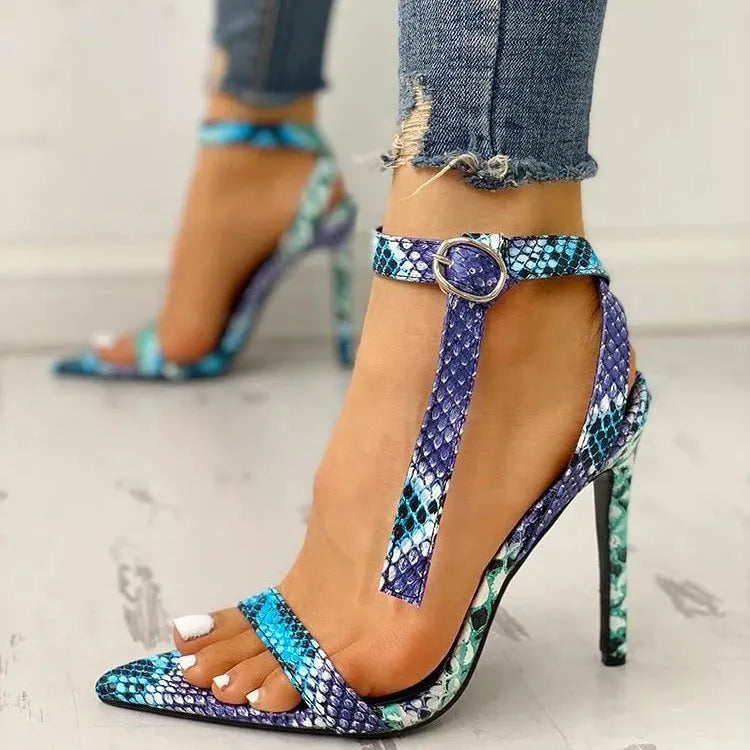 Blue women's high heels with a buckle strap and decorative hollow out design on a pointed toe.