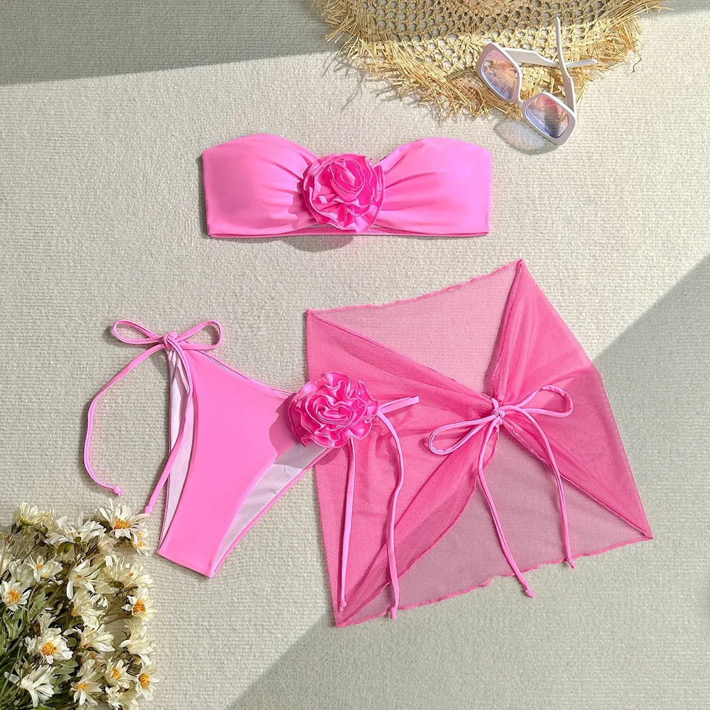 Women's pink tube top swimsuit with a large 3D flower, matching pants, and a skirt.