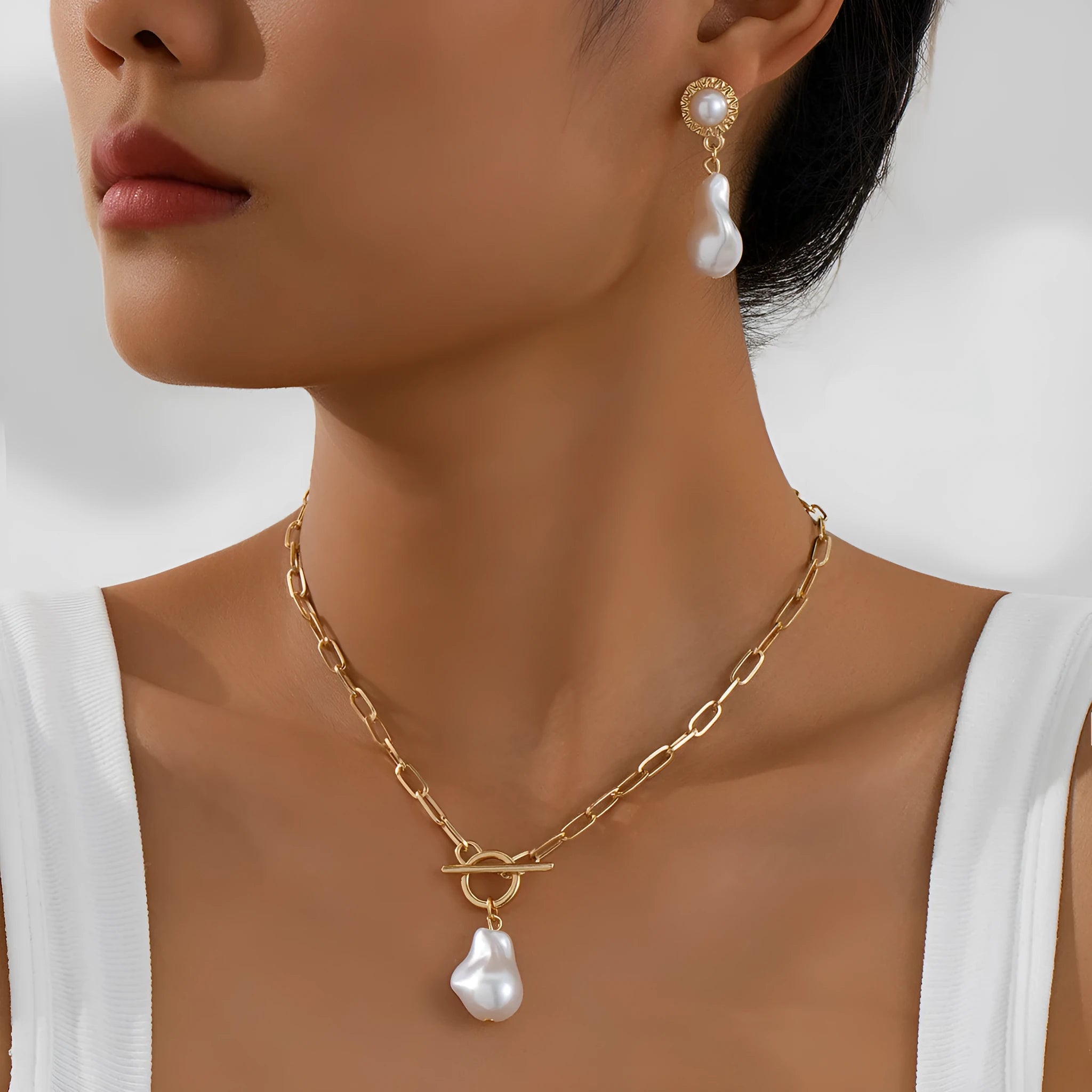 Gold retro baroque style necklace and earring set with pearl details on a white background.