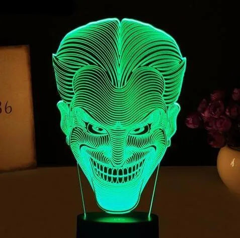 A 3D acrylic LED table lamp with a remote control on a desk, showing its colourful gradient light mode.