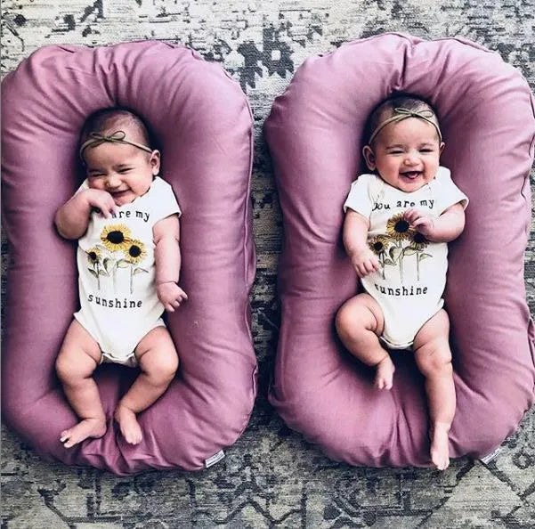 Beige portable baby nest cot cushion measuring 75cm by 45cm on a floor.