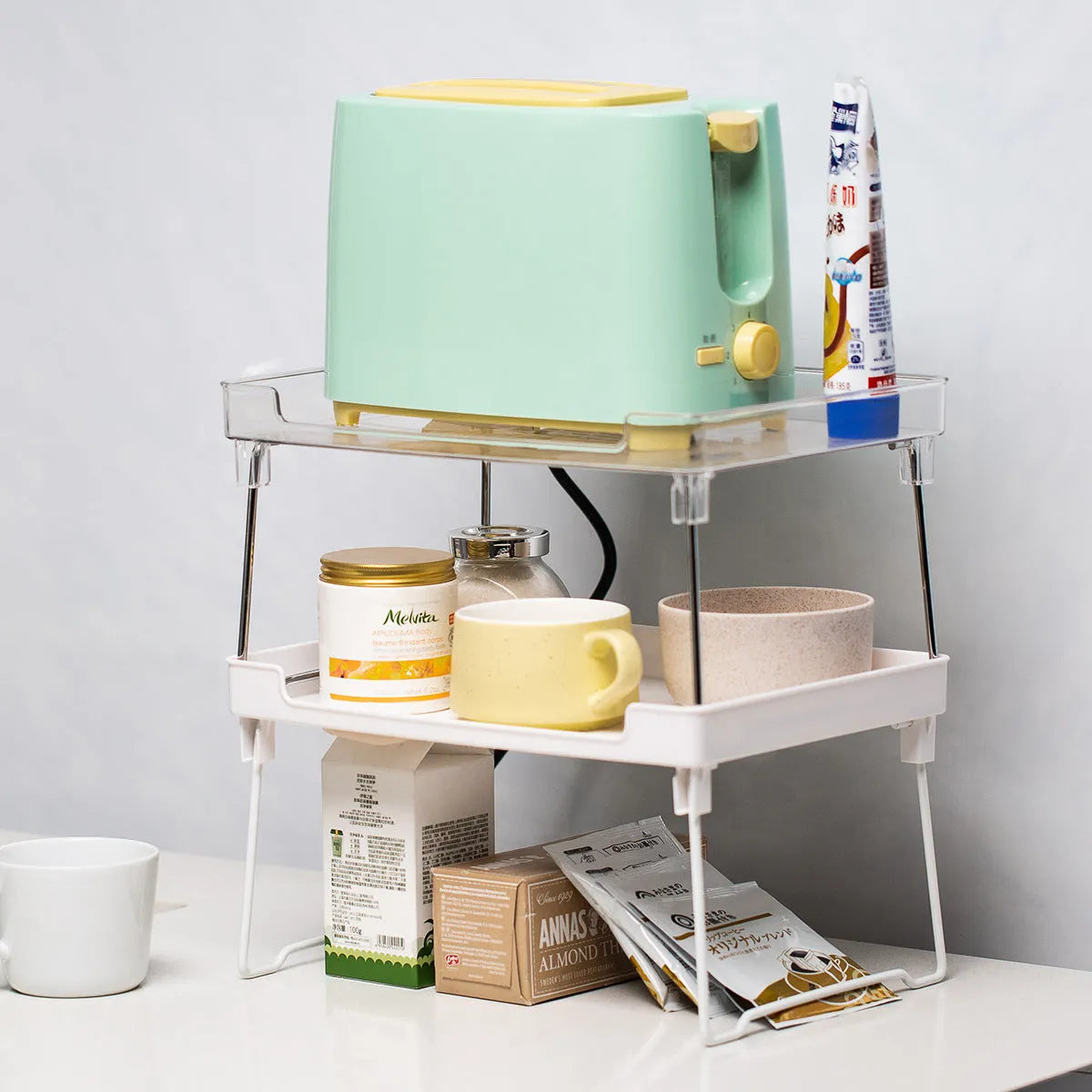 Transparent plastic kitchen supplies rack on a white countertop holding small items