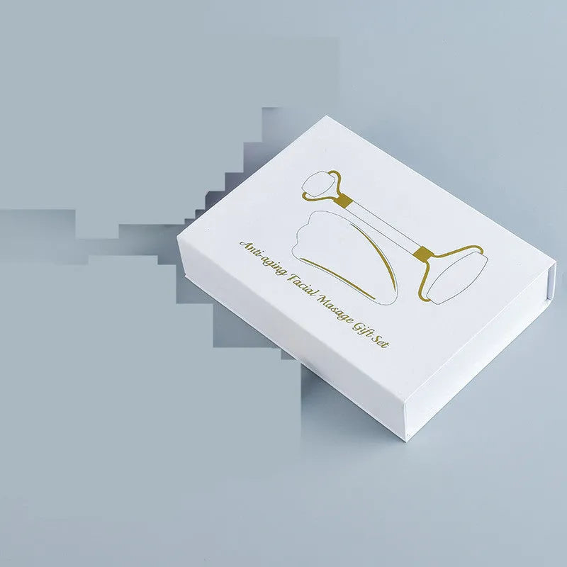 White jade double-headed facial roller and gua sha scraping board set on a storage tray.