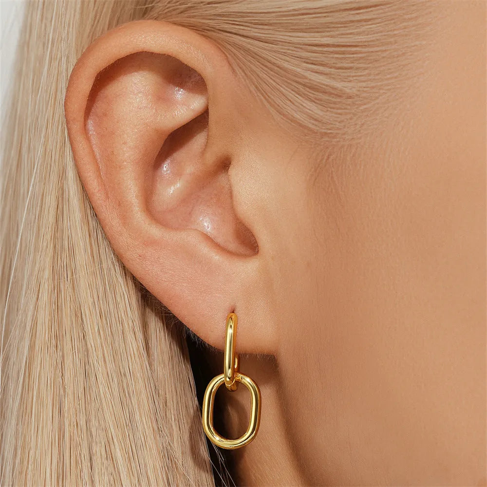 A pair of golden brass diamond-shaped earclip earrings with a round geometric design.