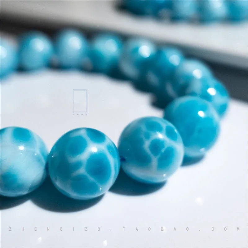 Blue Maillard-style Bodhi bracelet with a sea-pattern crystal stone and pearl accents on a wrist.