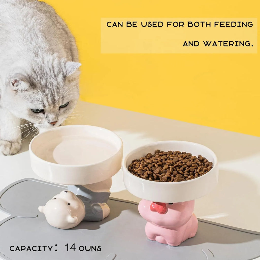 Raised ceramic cat bowl with animal design in pink, yellow, or white, showing wide feeding surface and elevated base.