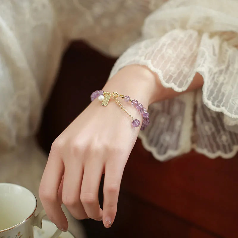 Natural crystal bracelet with romantic lavender amethyst beads, available in dark or light colour, on a plain background