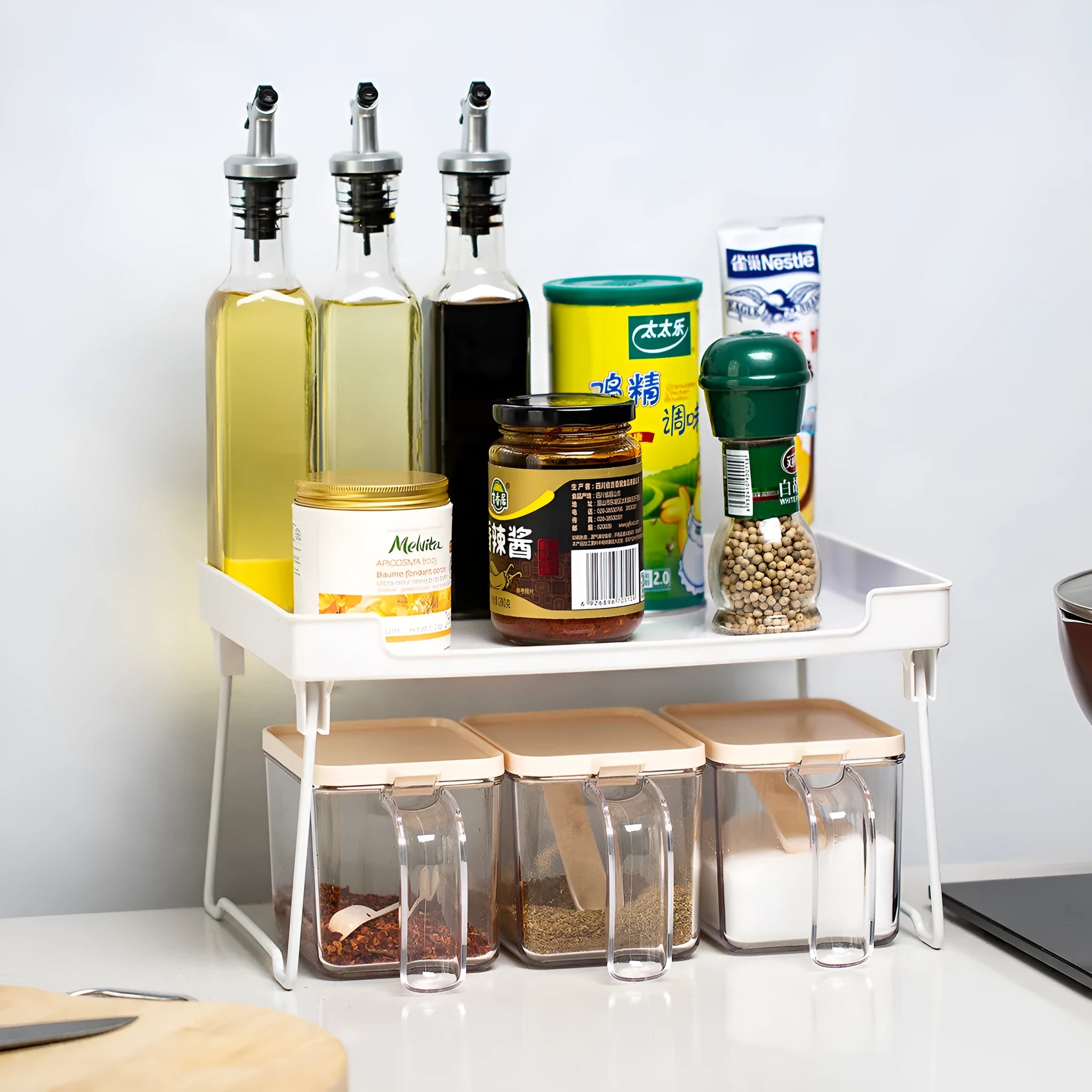 Transparent plastic kitchen supplies rack on a white countertop holding small items