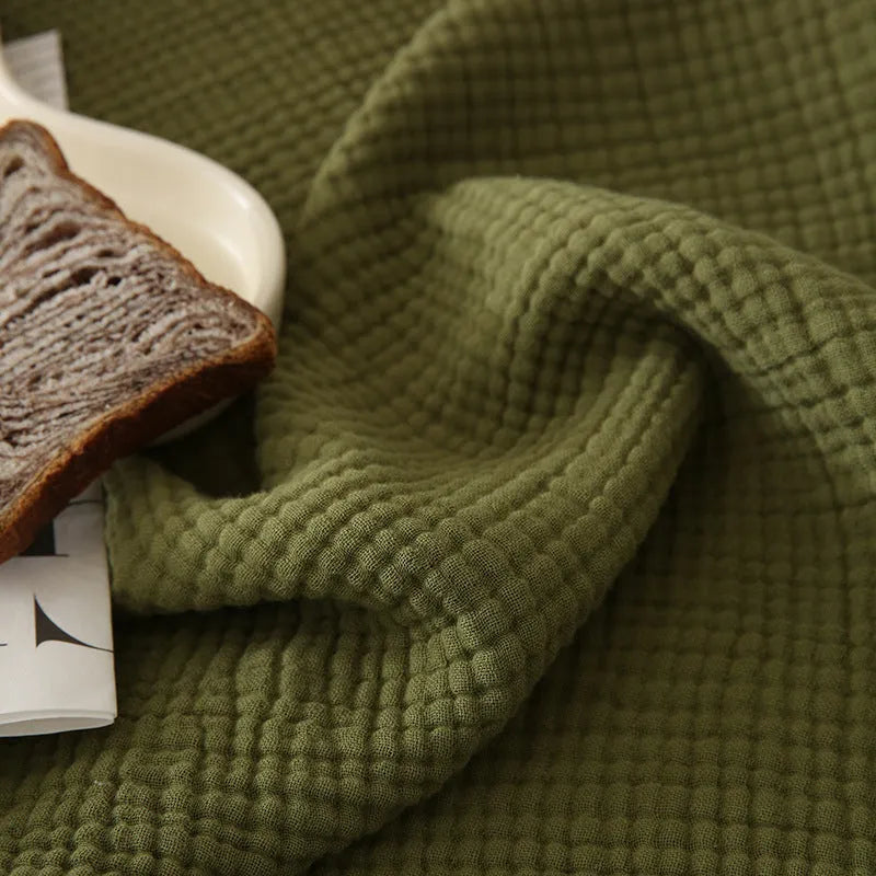 Cotton four-layer gauze throw blanket with tassel edges shown in avocado green colour.