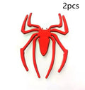 Three-dimensional metal spider bumper sticker in metallic finish on a car bumper.