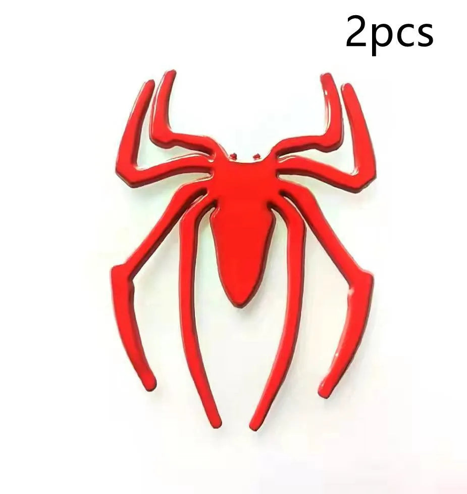 Three-dimensional metal spider bumper sticker in metallic finish on a car bumper.