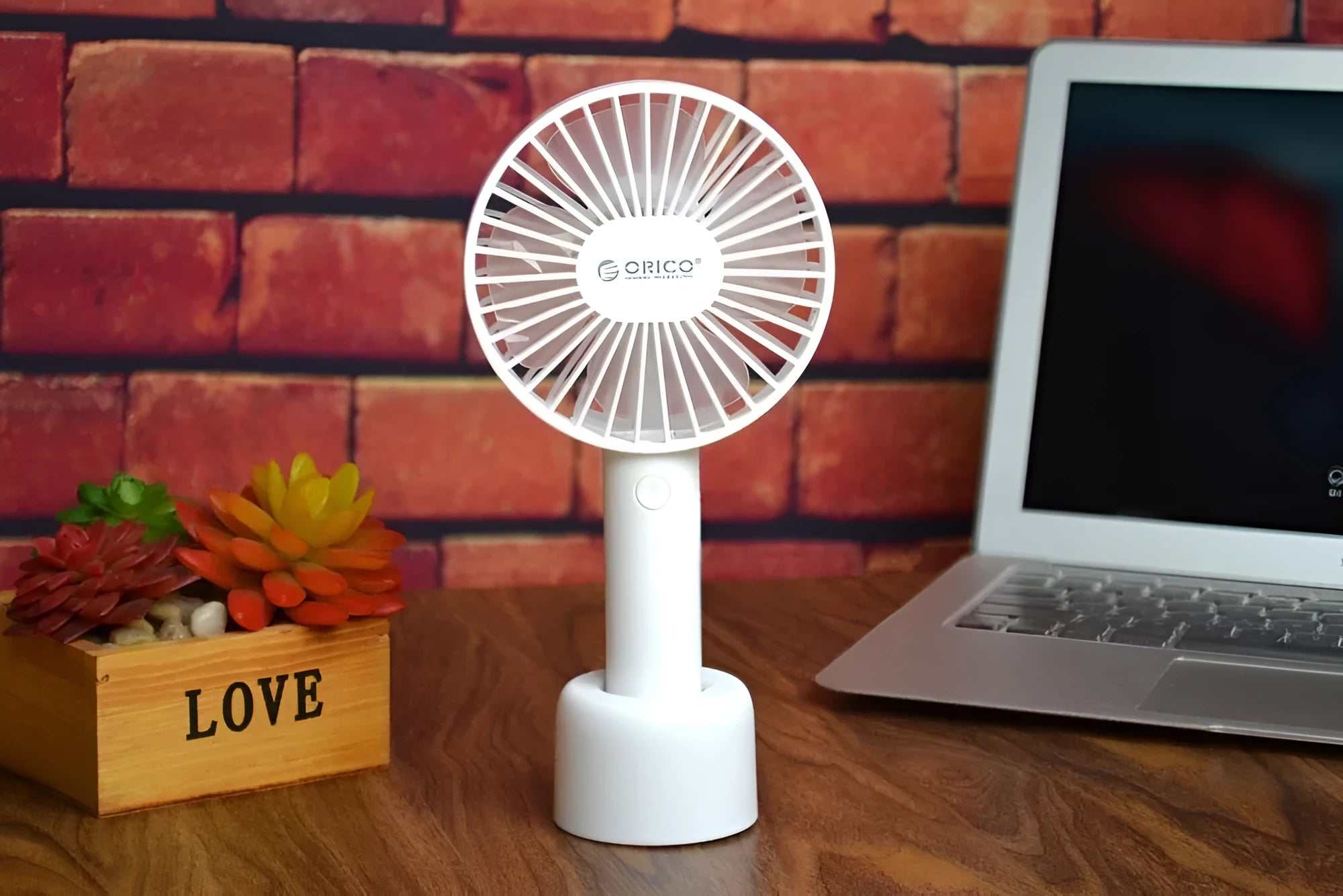 White ORICO FH1 handheld USB rechargeable small fan with three-speed buttons on a desktop.