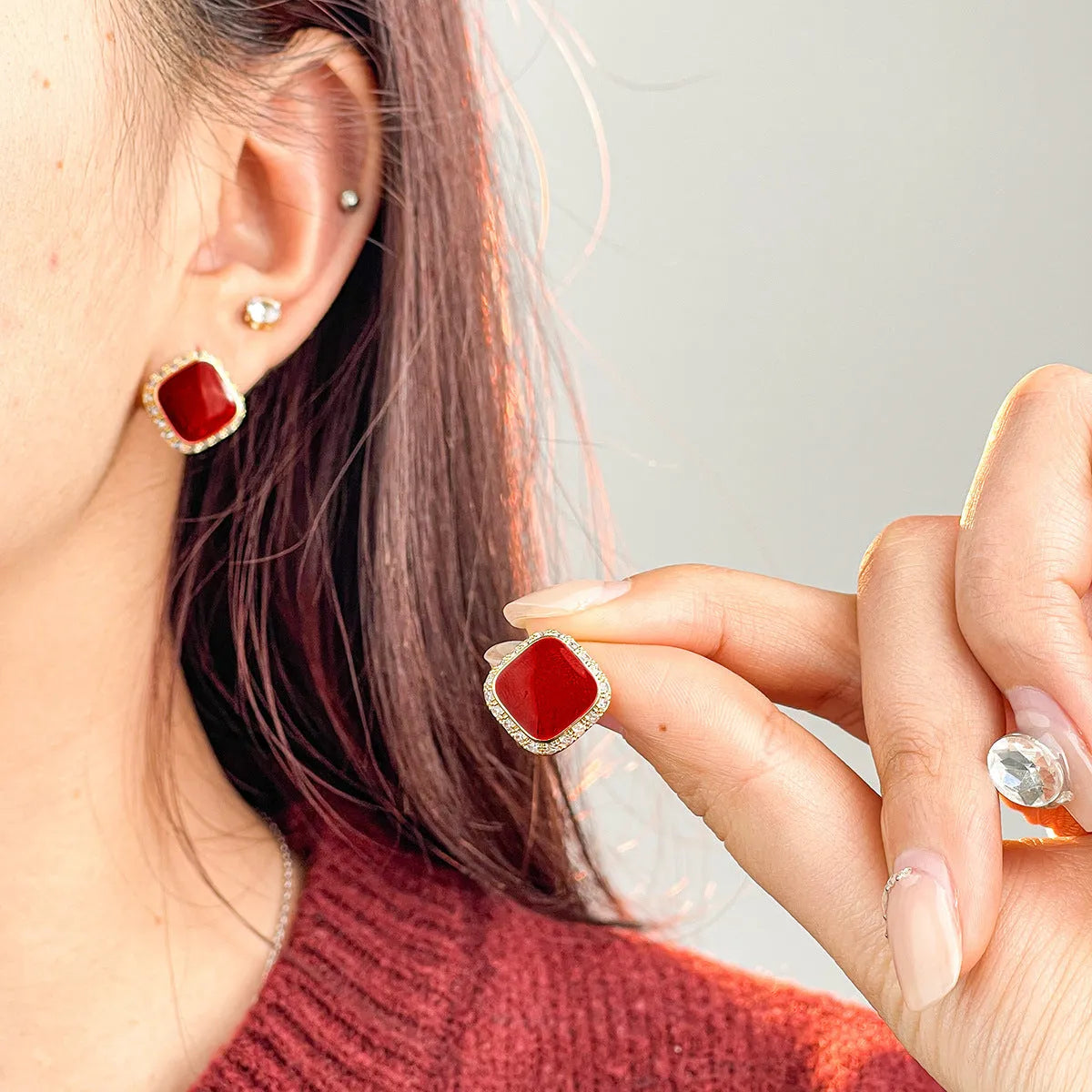 A pair of red geometric square alloy earrings with inlaid detailing on a white background.