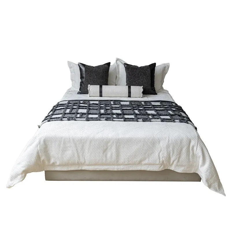 Modern minimalist grey and white plaid bed runner blanket set with matching pillow on a bed.