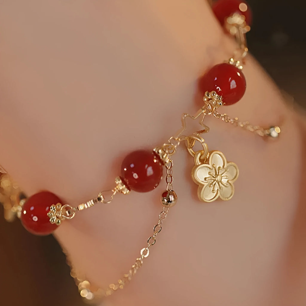 Red agate double layer bracelet with peach blossom charm on an adjustable elastic cord.