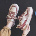 Women's low-top pink and white sneakers with a rubber sole and imitation leather lining.