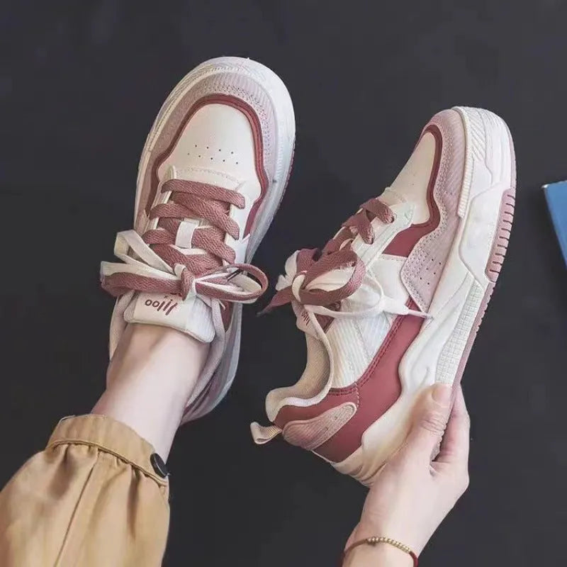 Women's low-top pink and white sneakers with a rubber sole and imitation leather lining.