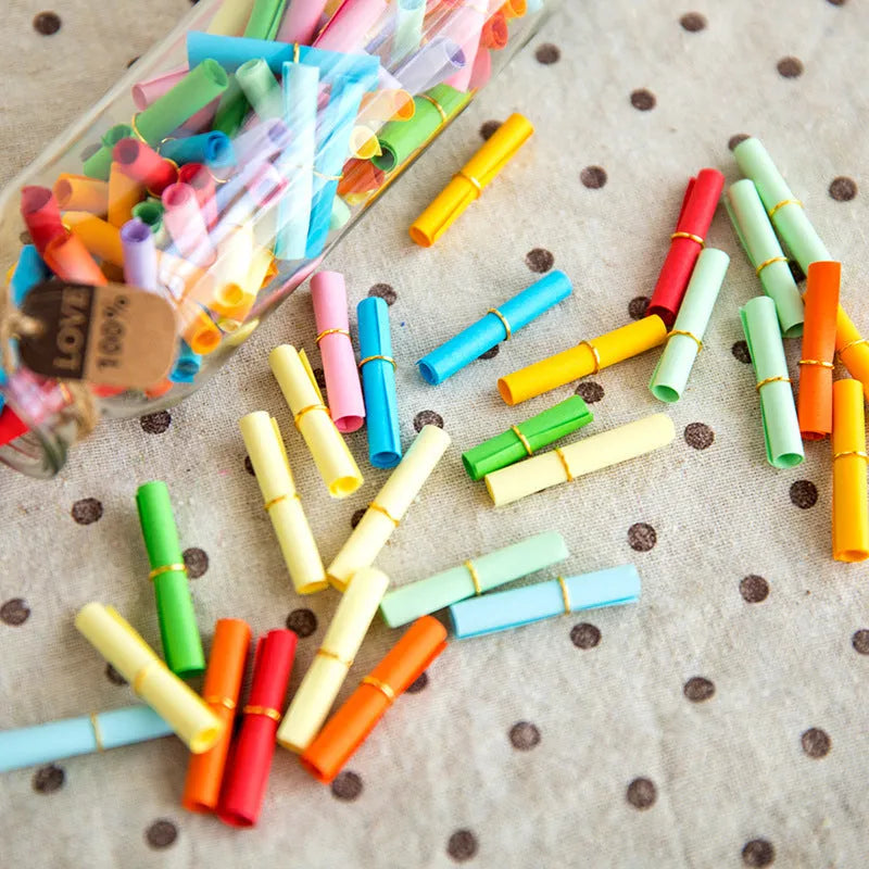 Assorted colour mini paper scrolls with metal eyelets in sizes 5x5cm, 3x7cm, 4x7cm, and 7x7cm for drift bottle messages.