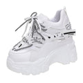 White and black women's low-top platform sports shoes with cross-strap and mesh design on a rubber sole.